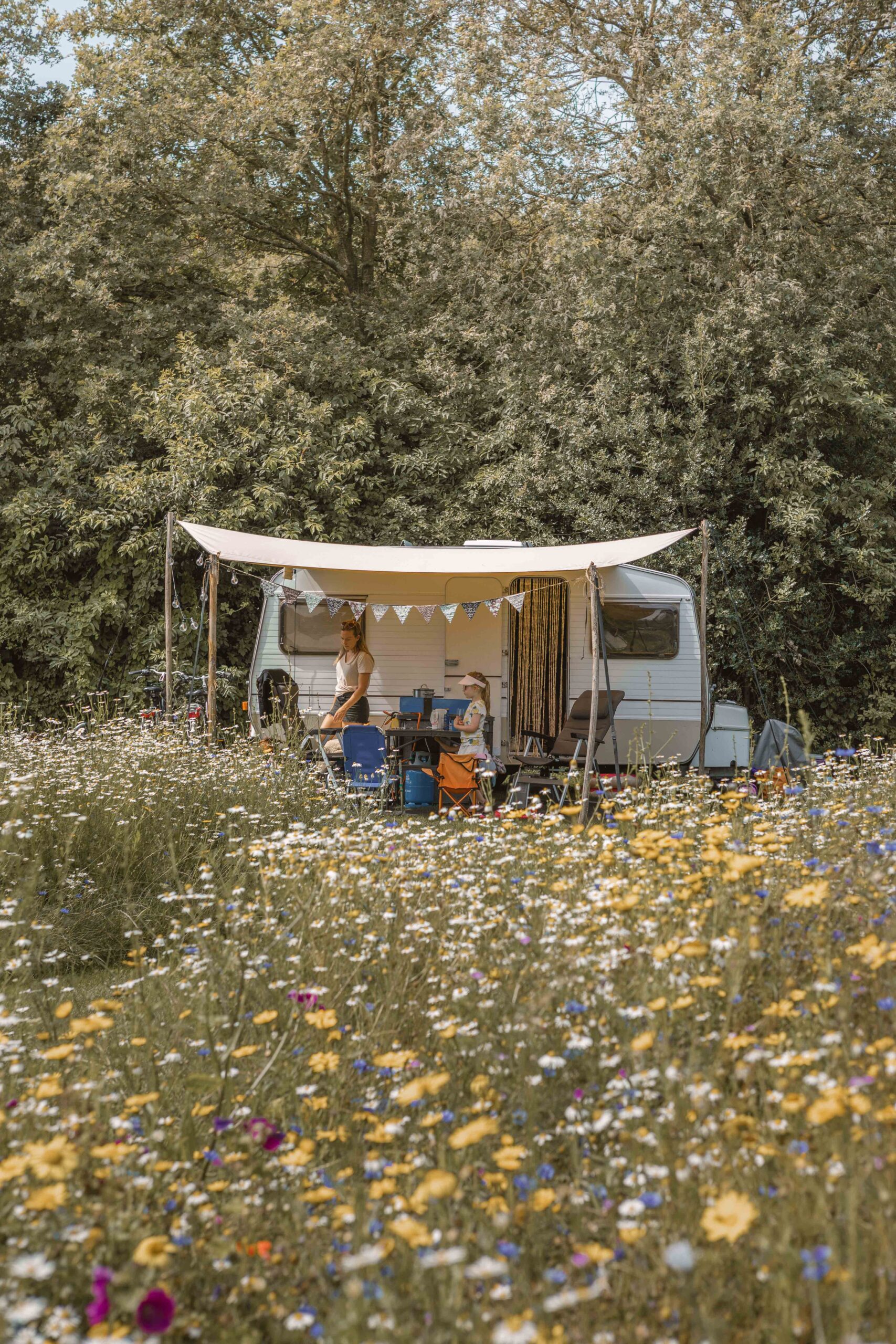 Gezin voor caravan met slingers op kampeerveld Bloemenweide van Lemeler Esch natuurcamping