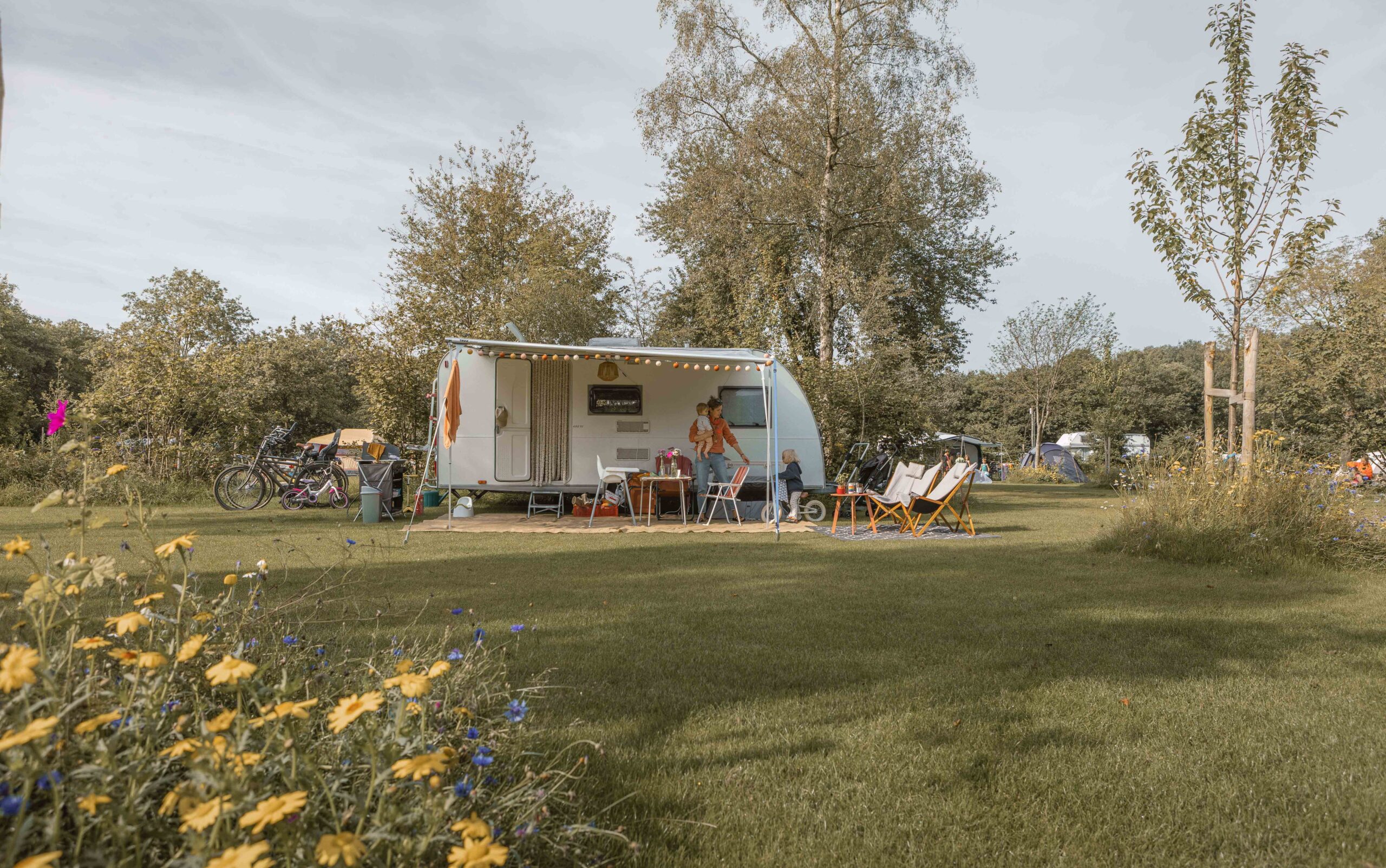 Moeder, peuter en baby voor de caravan op kampeerveld Boomgaard bij Lemeler Esch natuurcamping