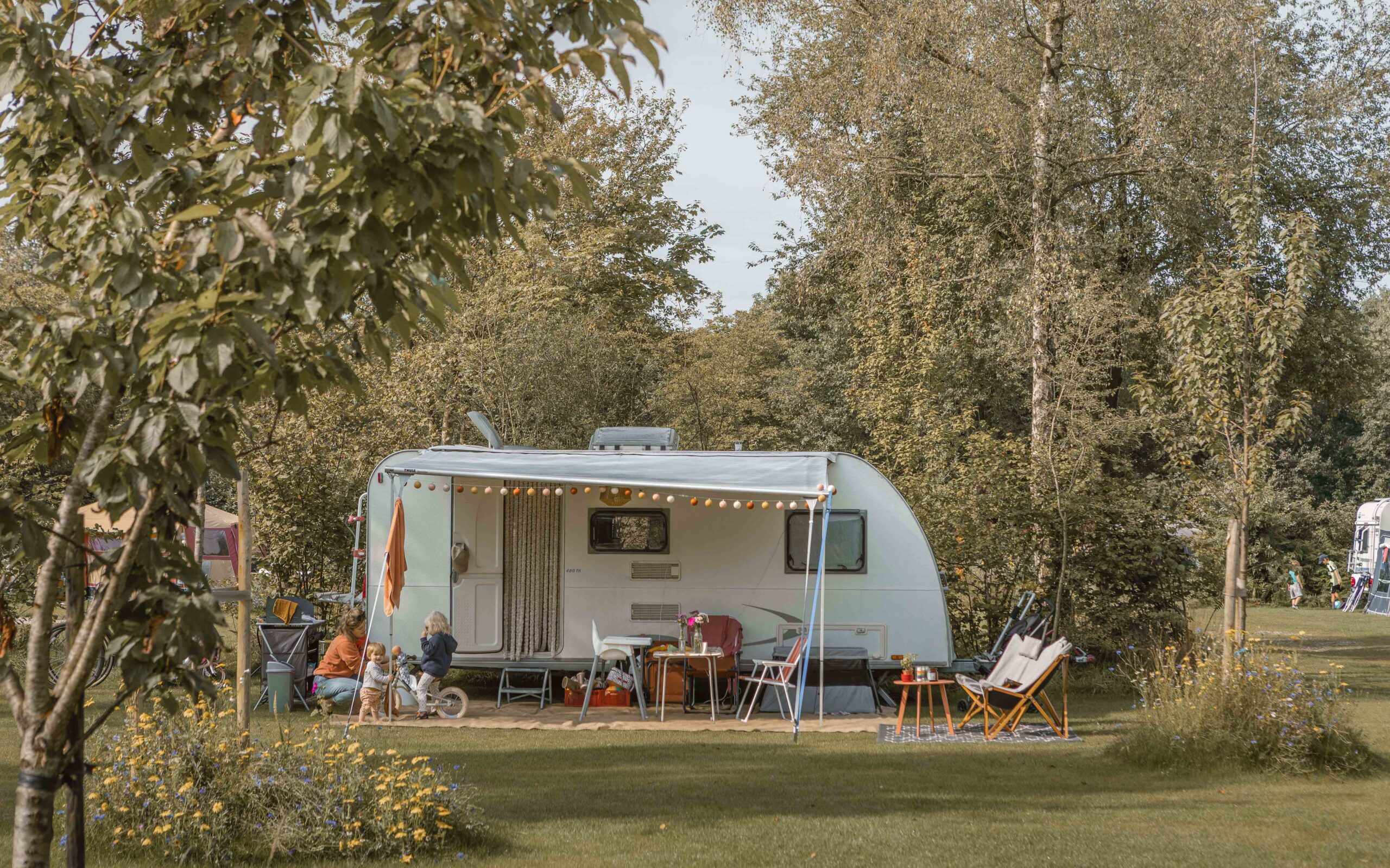 Moeder, peuter en baby voor de caravan op kampeerveld Bloemenweide bij Lemeler Esch natuurcamping