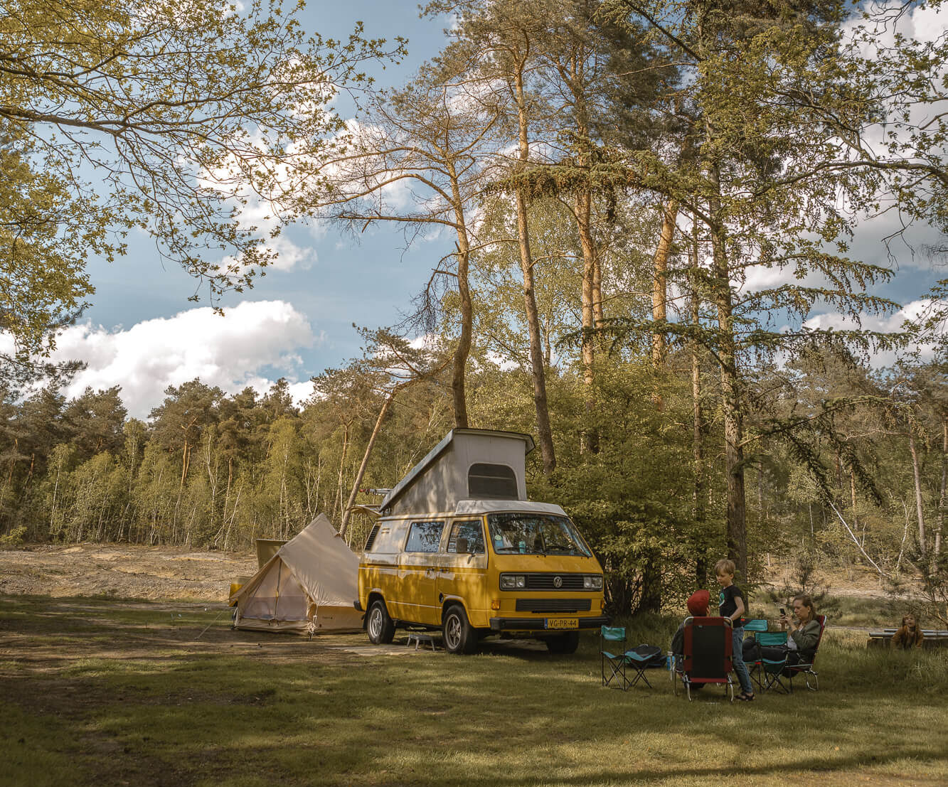 Gezin bij camperbus op de bosplaats bij Lemeler Esch natuurcamping