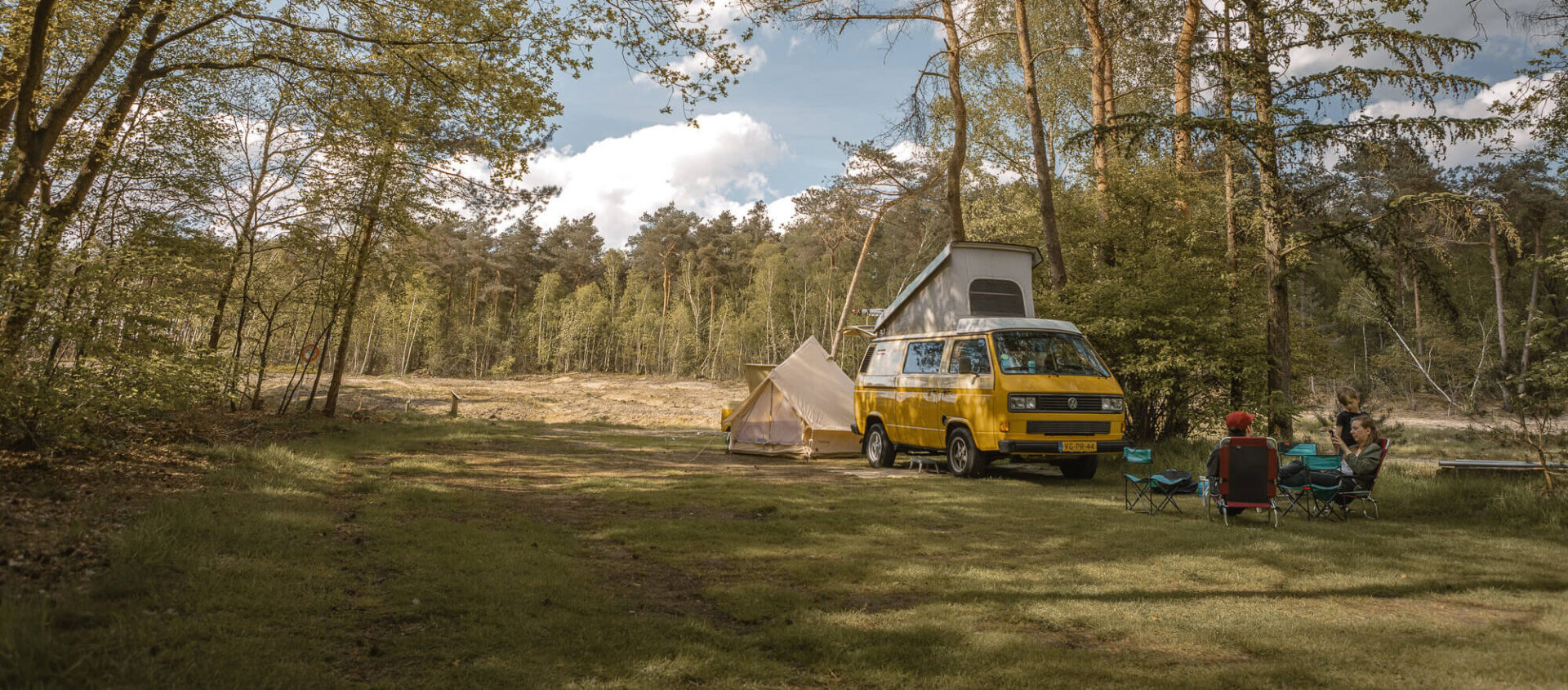 Gezin bij camperbus op de bosplaats bij Lemeler Esch natuurcamping
