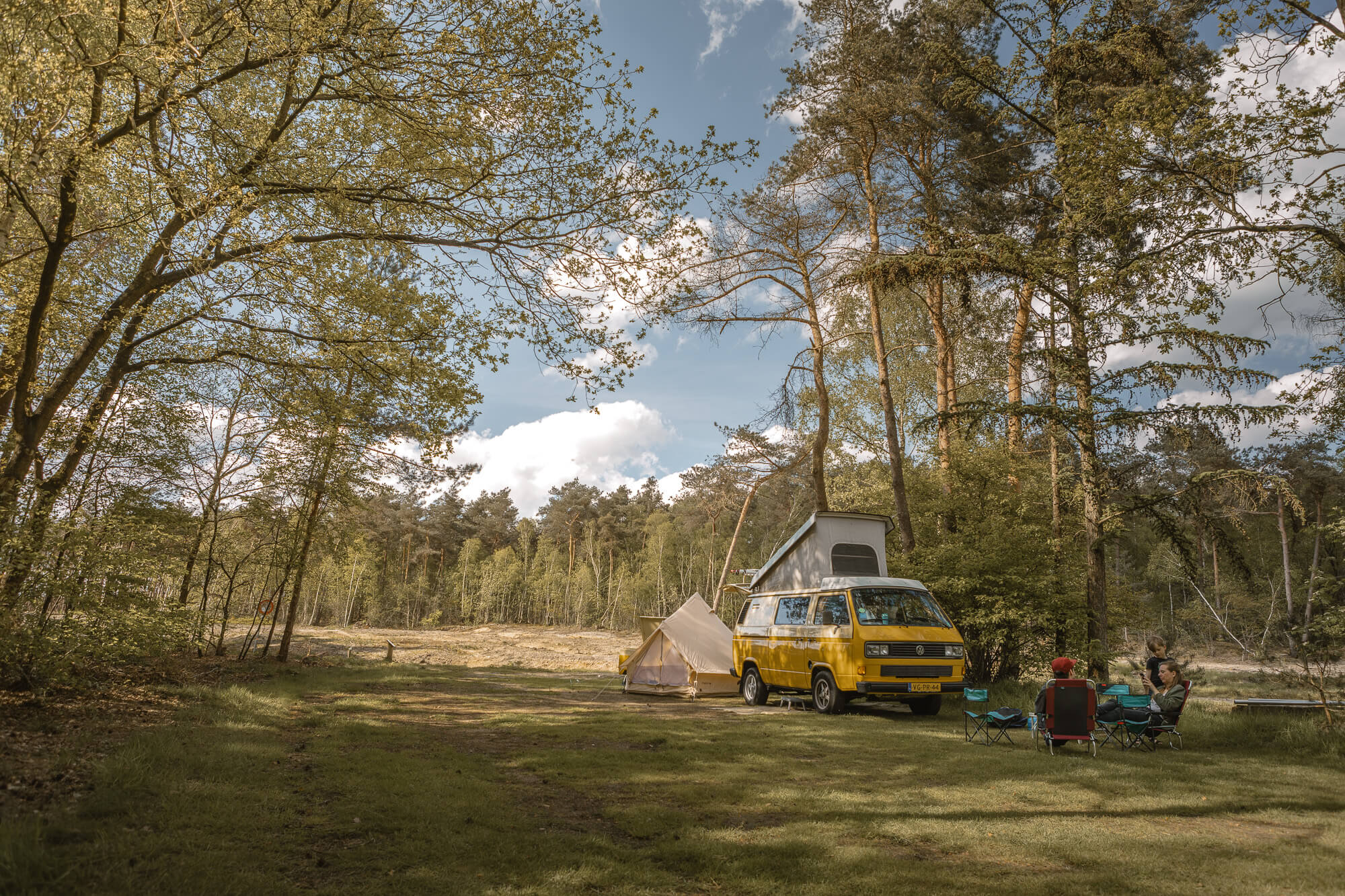Gezin met camperbus op de bosplaats bij Lemeler Esch natuurcamping in Overijssel