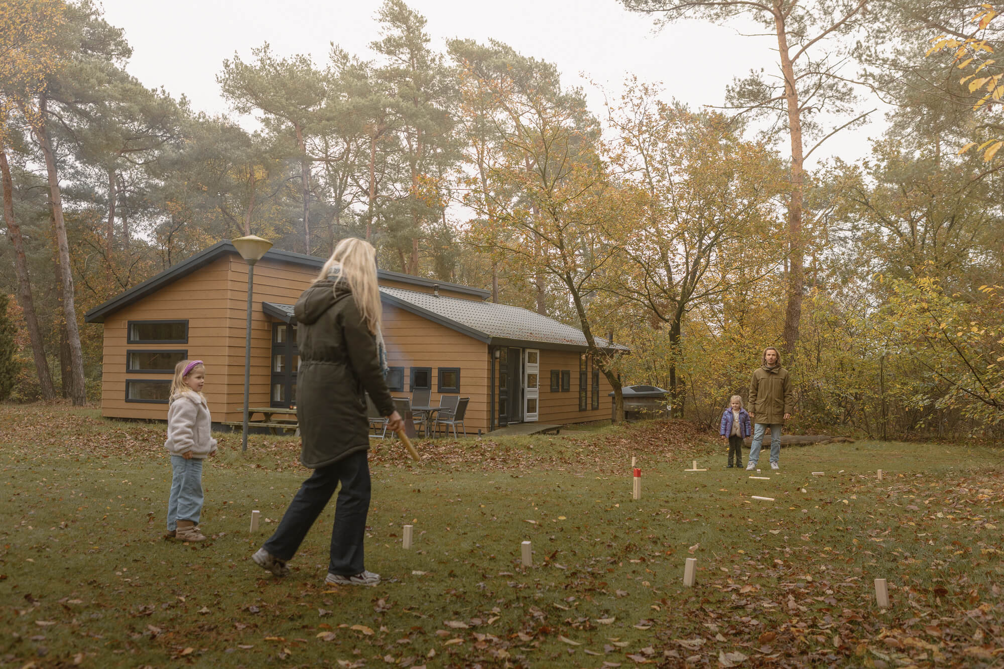 Gezin speelt kubb spel bij bungalow aan de bosrand bij Lemeler Esch natuurcamping