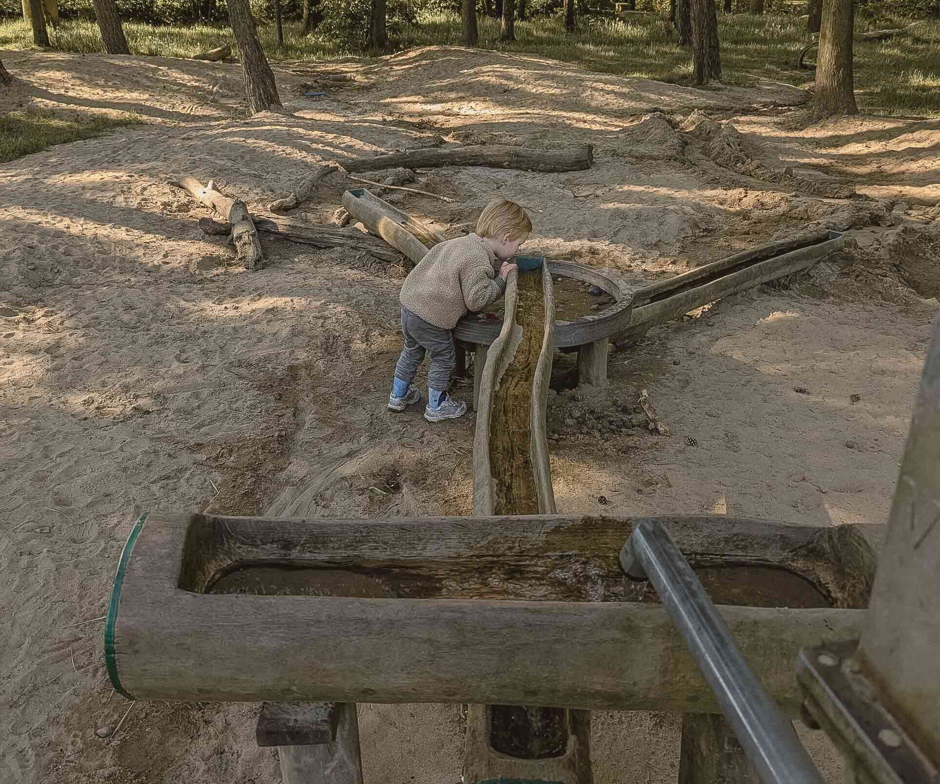 Foto van Speeltuinchecker kind bij waterbaan in het speelbos bij Lemeler Esch natuurcamping