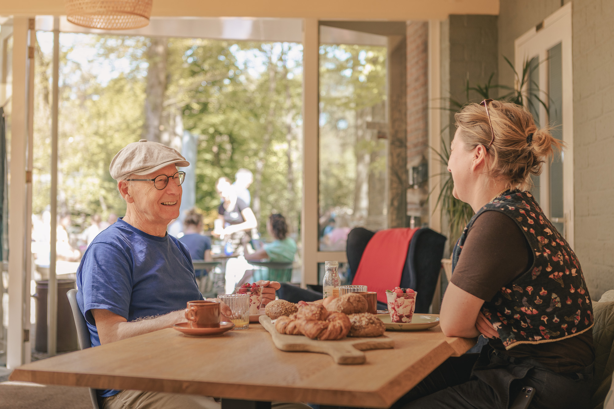 Gasten aan tafel met brunchplank in de serre van Boscafé Lemeler Esch