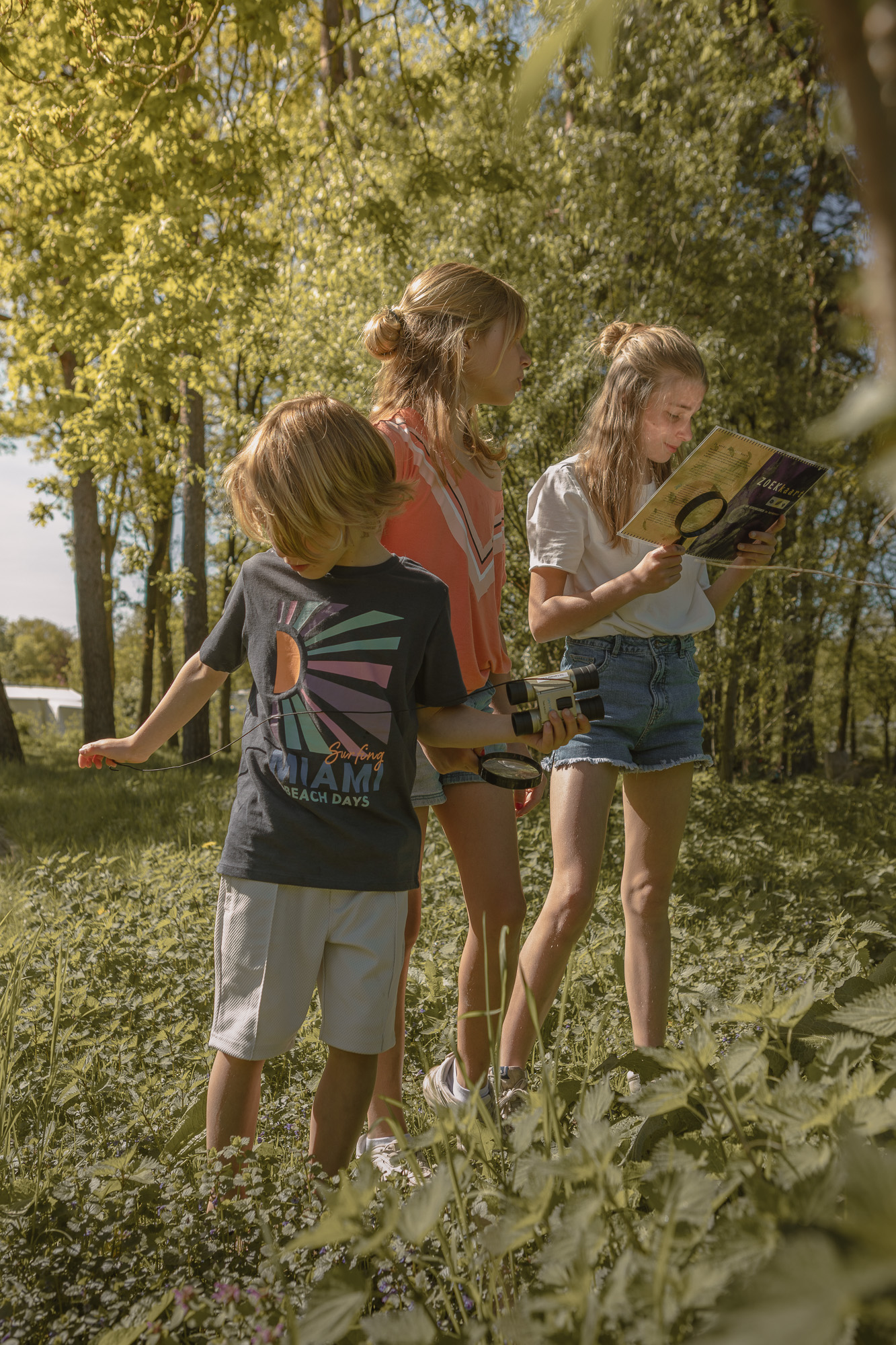 Kinderen met zoekkaart en vergrootglas in speelbos bij Lemeler Esch