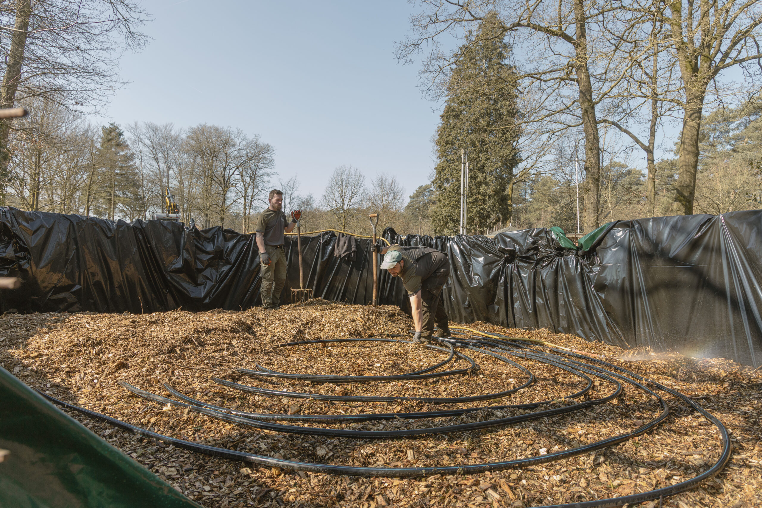De buitendienst is bezig met het vullen van de biomeiler bij natuurcamping Lemeler Esch
